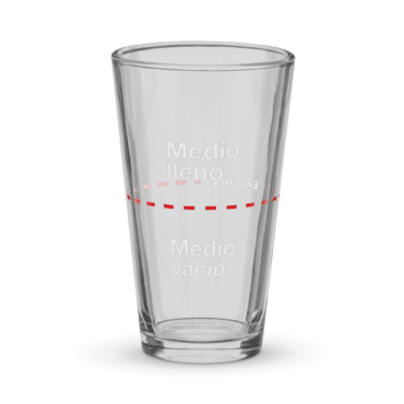 Vaso medio lleno de vidrio visto de frente sobre fondo blanco.