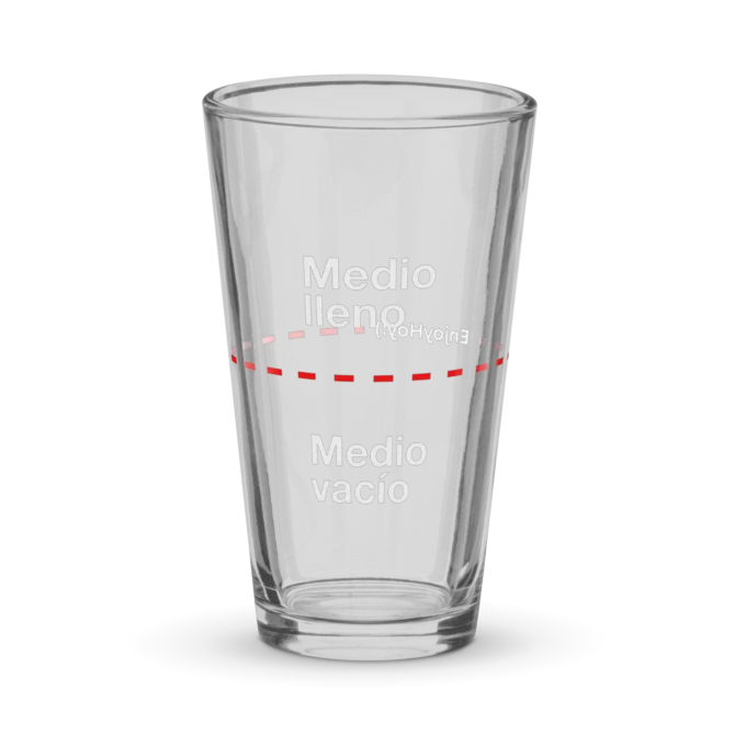 Vaso medio lleno de vidrio visto de frente sobre fondo blanco.