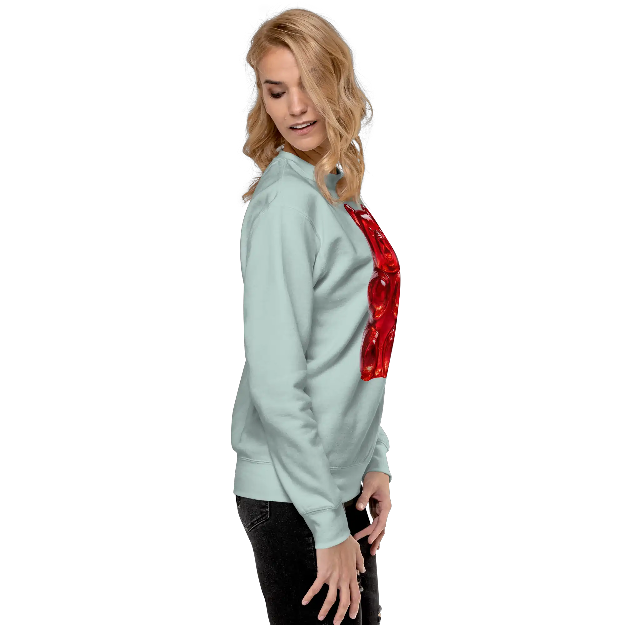 Mujer rubia de perfil con la sudadera verde agua y el borde del osito rojo visible, pantalón negro