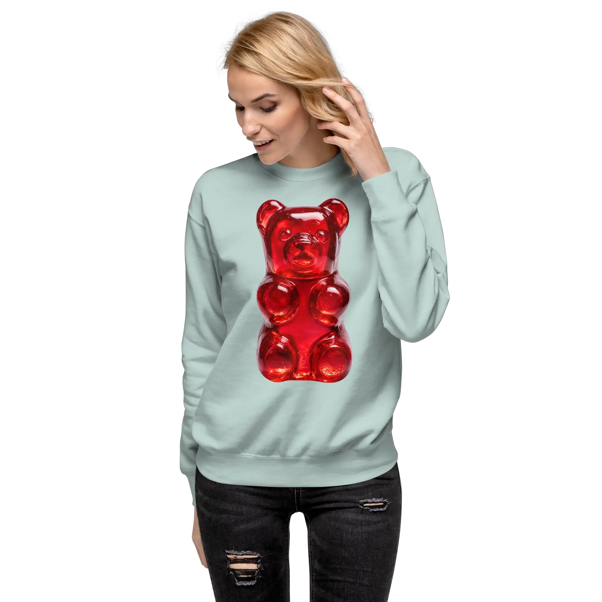 Mujer rubia sonriendo y tocándose el cabello con la sudadera de osito de gomita y pantalón negro